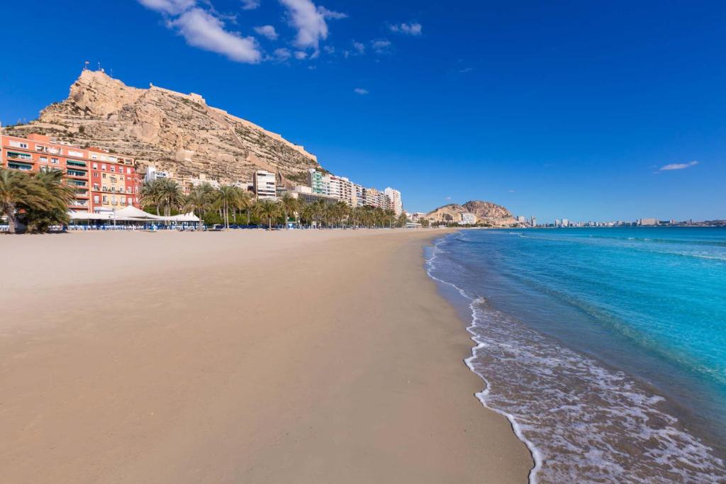 a sandy beach with buildings and the ocean at Gutierrez Apartment in Alicante
