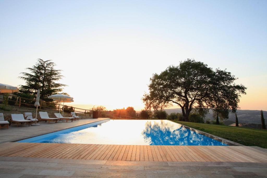 a swimming pool with a sunset in the background at Vitabella Toscana in Seggiano