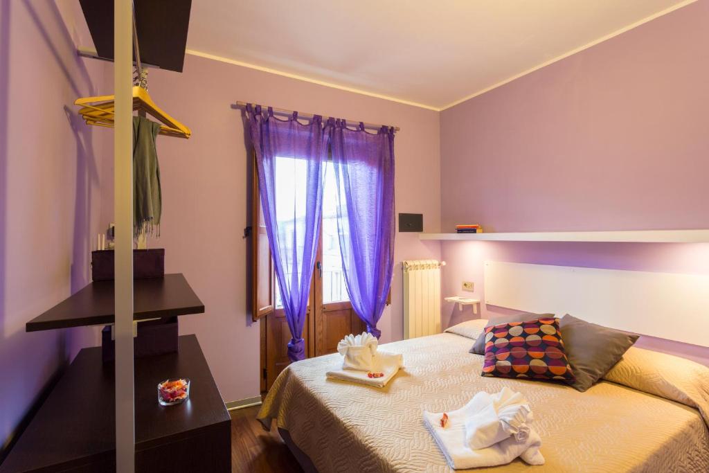 a bedroom with a bed and a window with purple curtains at Case Spazioscena - Euterpe in Castelbuono