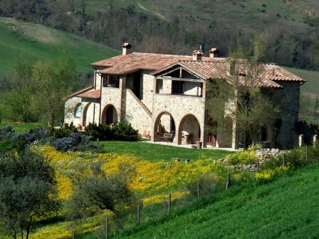 duży kamienny dom na trawiastym wzgórzu w obiekcie Agriturismo Pian di Frattina w mieście Fabro