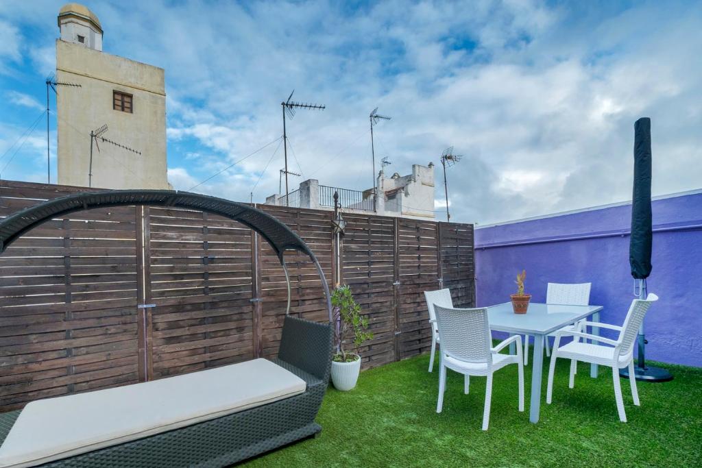 un patio con mesa, sillas y una valla en Atico soleado y céntrico, en Cádiz