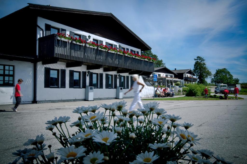 a woman walking in front of a building with flowers at Rasta Håby in Munkedal