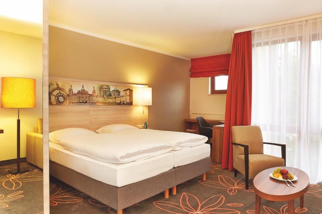 ハノーファーにあるH+ Hotel Hannoverのベッドと椅子のあるホテルの部屋