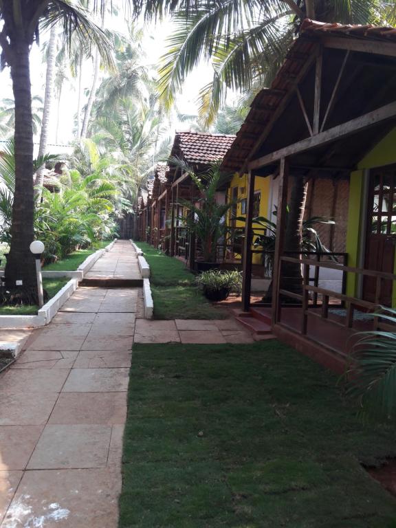 ścieżka prowadząca do ośrodka z palmami w obiekcie Shiva Cottages w mieście Mandrem