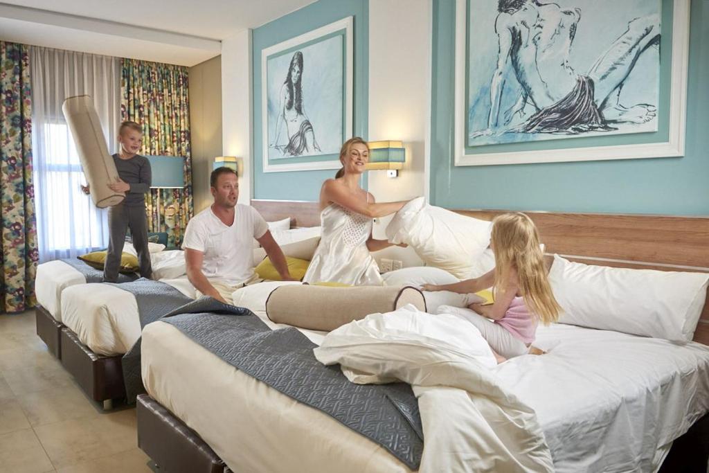 a family sitting on beds in a hotel room at Metcourt at Emperors Palace in Kempton Park