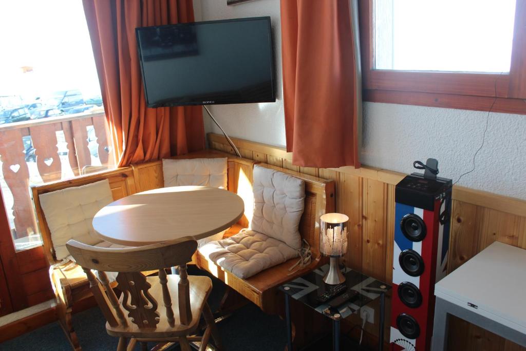 ティーニュにあるStudio cabine double balcon Tignes val claret ouvert toute l annéeのテーブル、テレビ、椅子が備わる客室です。