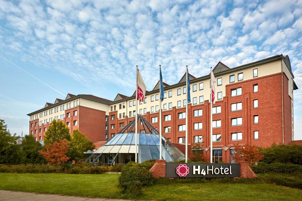 un bâtiment d'hôtel avec un panneau devant lui dans l'établissement H4 Hotel Hannover Messe, à Hanovre