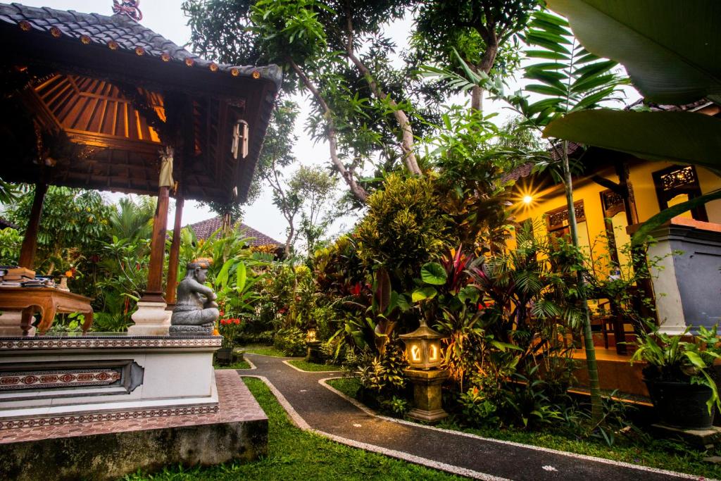 a garden in front of a house with a statue at Gusti Kaler House in Ubud