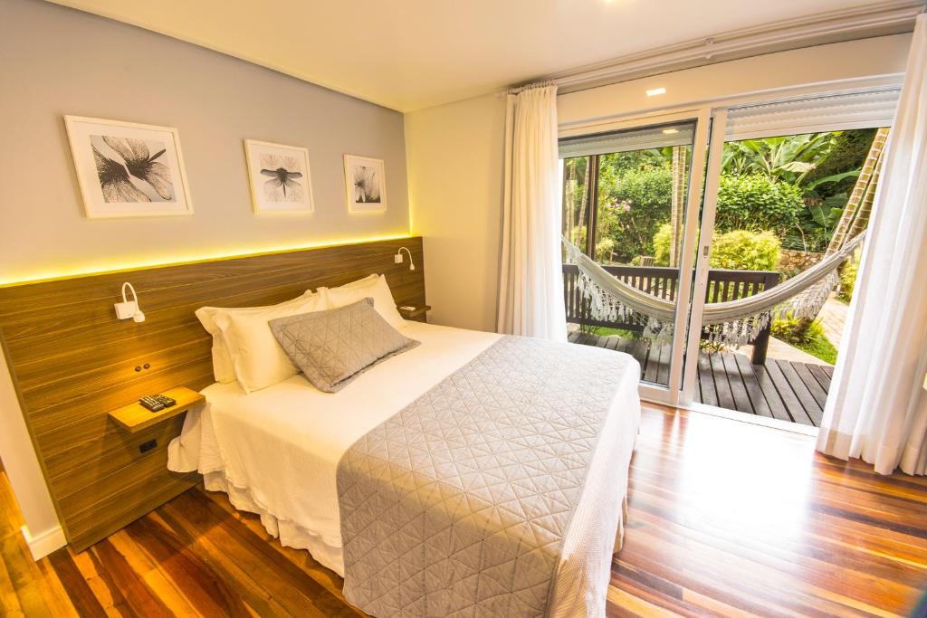 a bedroom with a bed and a large window at Hospedaria das Brisas in Praia do Rosa