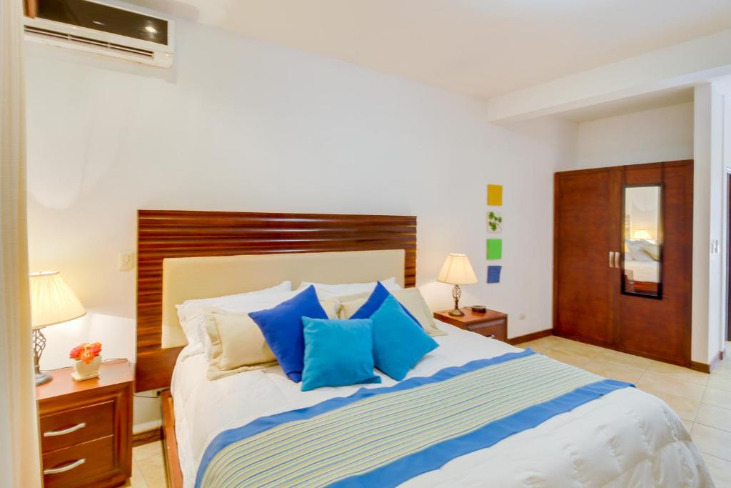 1 dormitorio con 1 cama grande con almohadas azules en Ocotal Beach Club Hotel 1, en Guanacaste
