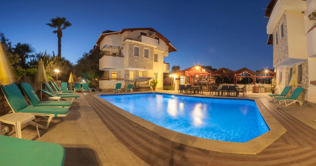 a swimming pool with chairs and a building at Villa Gardenia in Dalyan