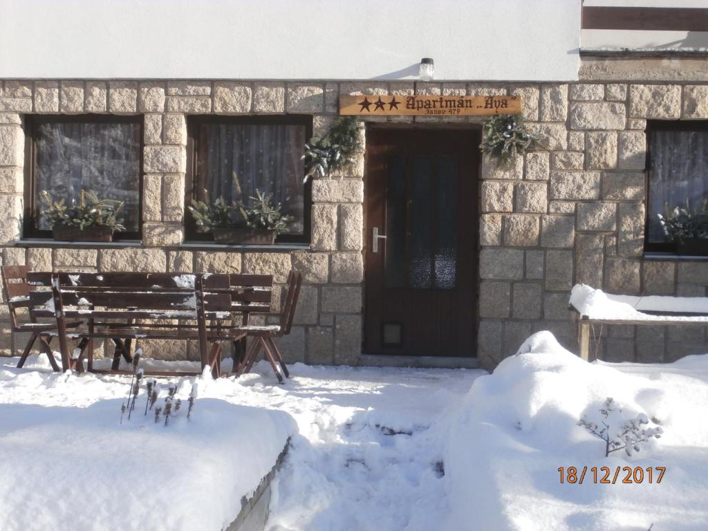 a building with a wooden door in the snow at Apartman Aya in Janov nad Nisou