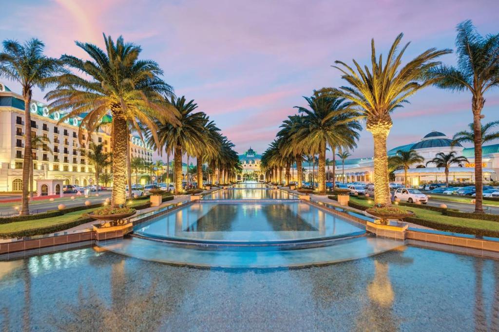 a fountain in a street with palm trees at Peermont D'oreale Grande at Emperors Palace in Kempton Park