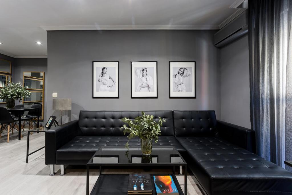 un soggiorno con divano nero e tavolo di Holi-Rent Gran Poder a Siviglia