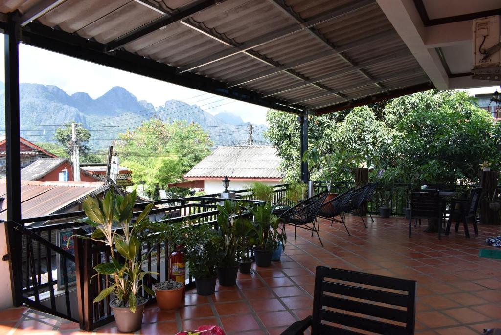 um pátio com cadeiras e plantas e montanhas ao fundo em Nice view guesthouse em Vang Vieng