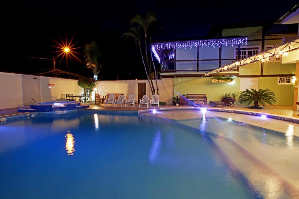 una gran piscina por la noche con luces en Recanto Vicks Flats en Ilhabela