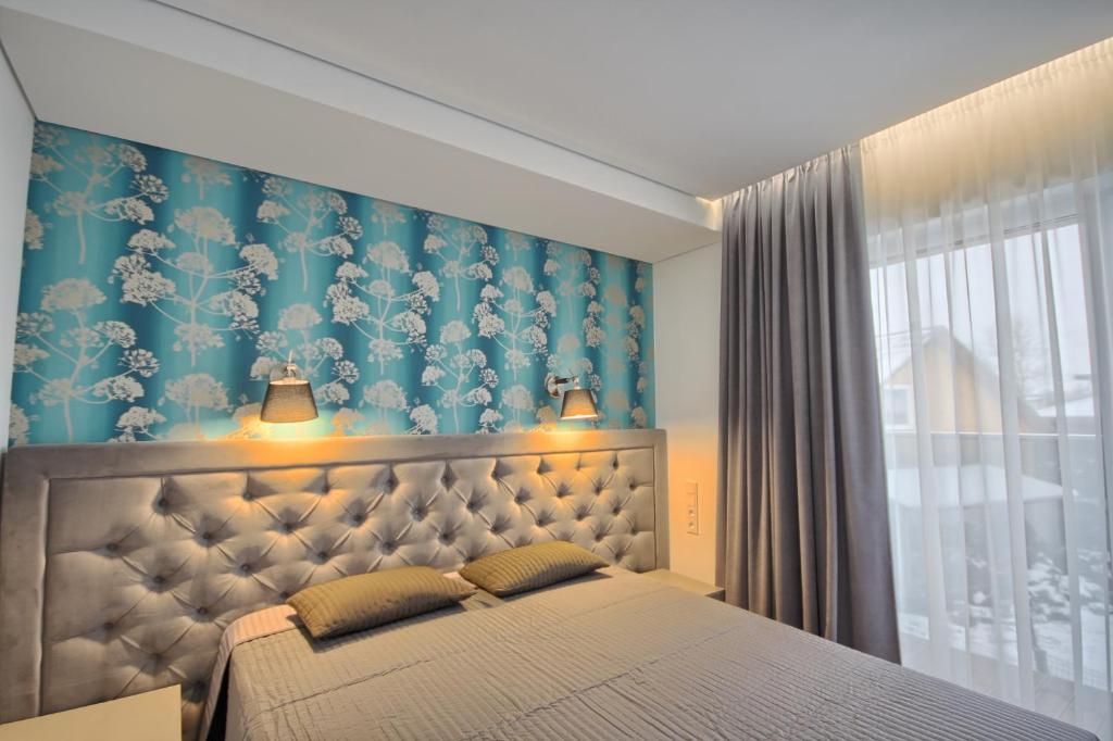 a bedroom with a bed with a blue and white wallpaper at Nikolas Apartamentai - Birstono 7 in Druskininkai