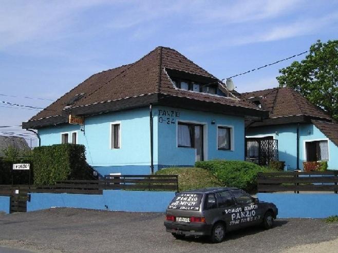 ein blaues Haus mit einem davor geparkt in der Unterkunft Domino Panzió in Székesfehérvár