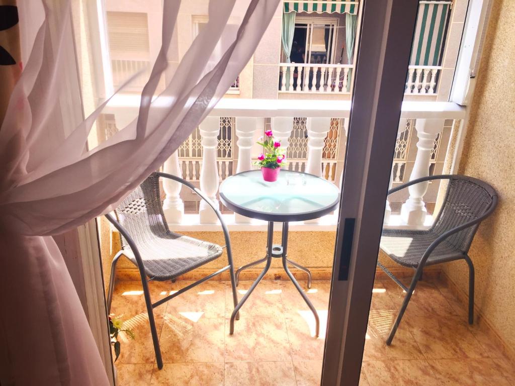 a small table and chairs on a balcony with a window at Apartamento San Pascual, 289 in Torrevieja