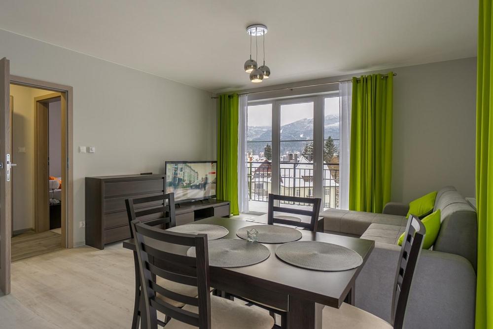 a dining room with a table and chairs and a couch at Villa Mountain View Apartamenty in Szklarska Poręba