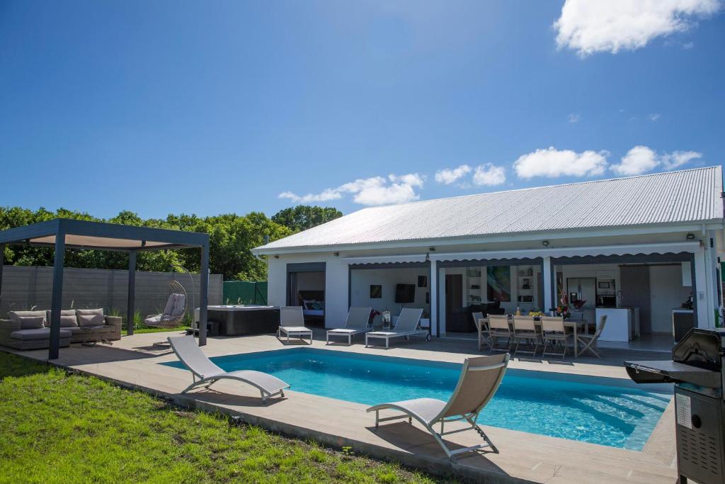 un patio trasero con piscina y sillas y una casa en Villa Blue Lagoon - Perle des Salines, en Saint-François