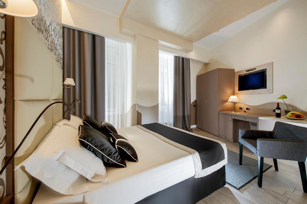 ローマにあるデメトラ ホテルのベッドとデスクが備わるホテルルームです。