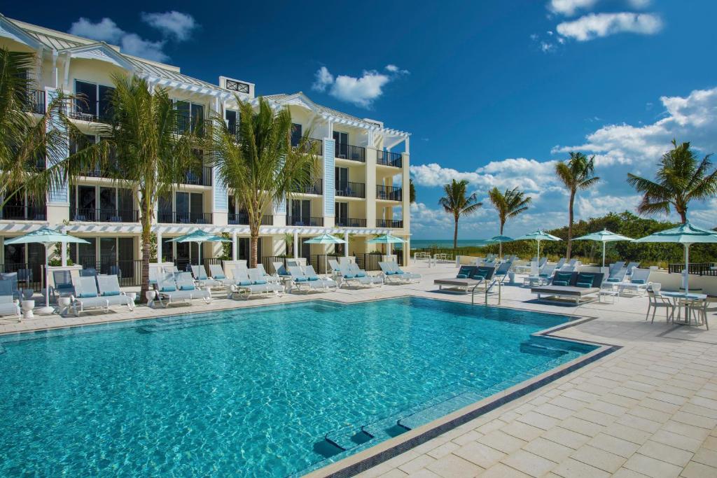 a resort with a pool and chairs and palm trees at Hutchinson Shores Resort & Spa in Jensen Beach
