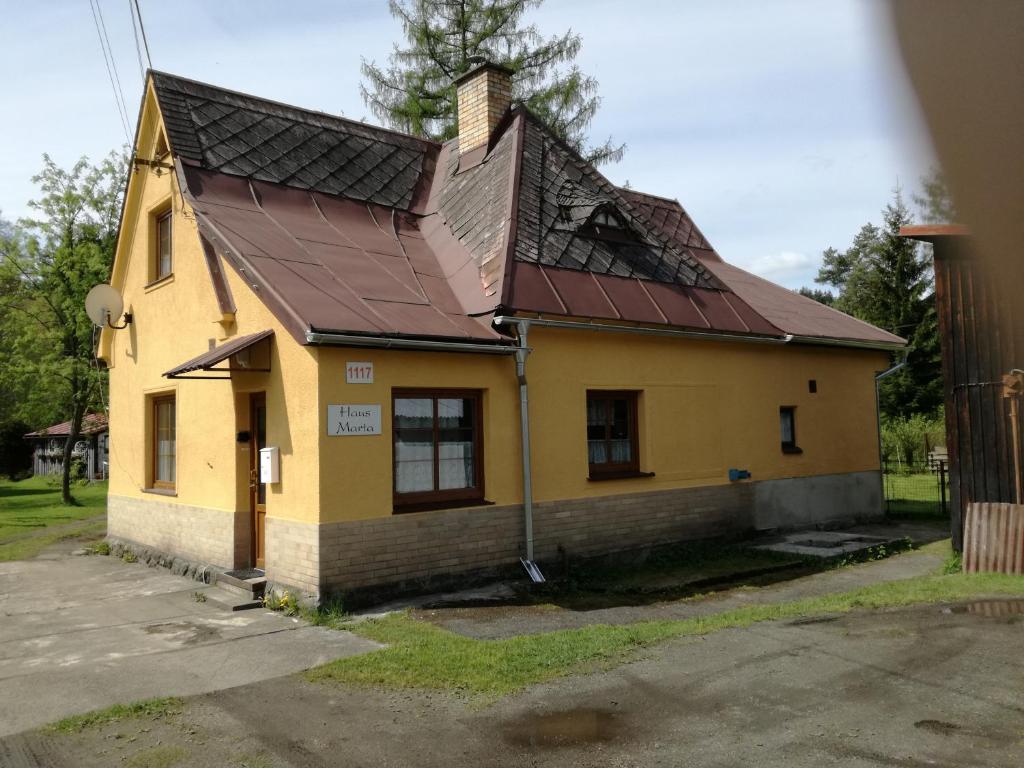 una casa amarilla con techo de metal en Haus Marta, en Smržovka