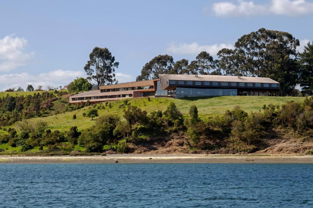 a house on top of a hill next to a body of water at Tierra Chiloe in San José