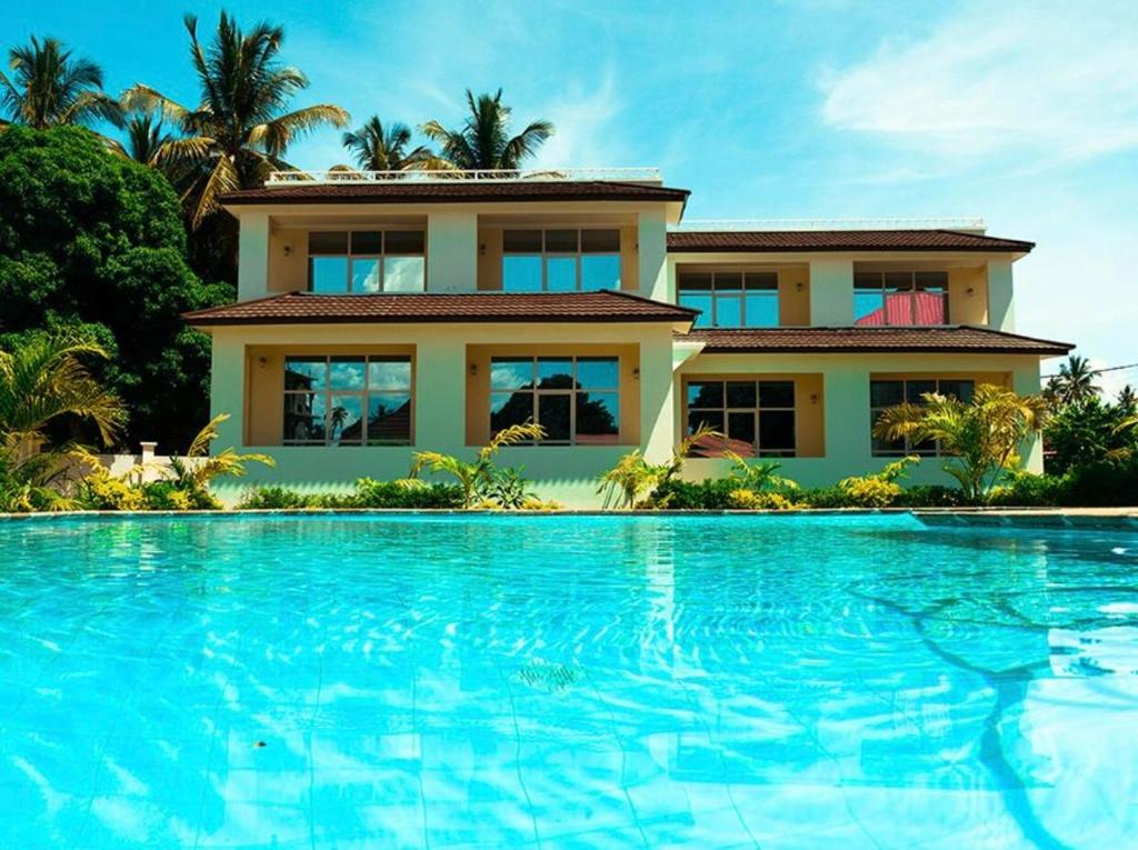 a house with a swimming pool in front of a house at Green Turaco in Zanzibar City