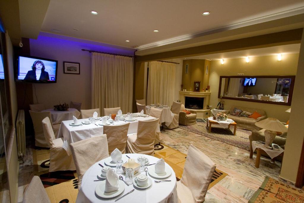 jadalnia z białymi stołami i krzesłami oraz telewizorem w obiekcie 40 Platania Hotel w mieście Loutra Edipsou