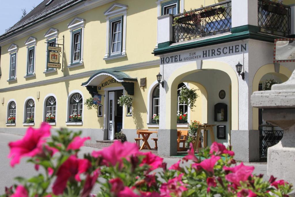 un edificio con flores rosas delante de él en Hotel zum goldenen Hirschen en Göstling an der Ybbs