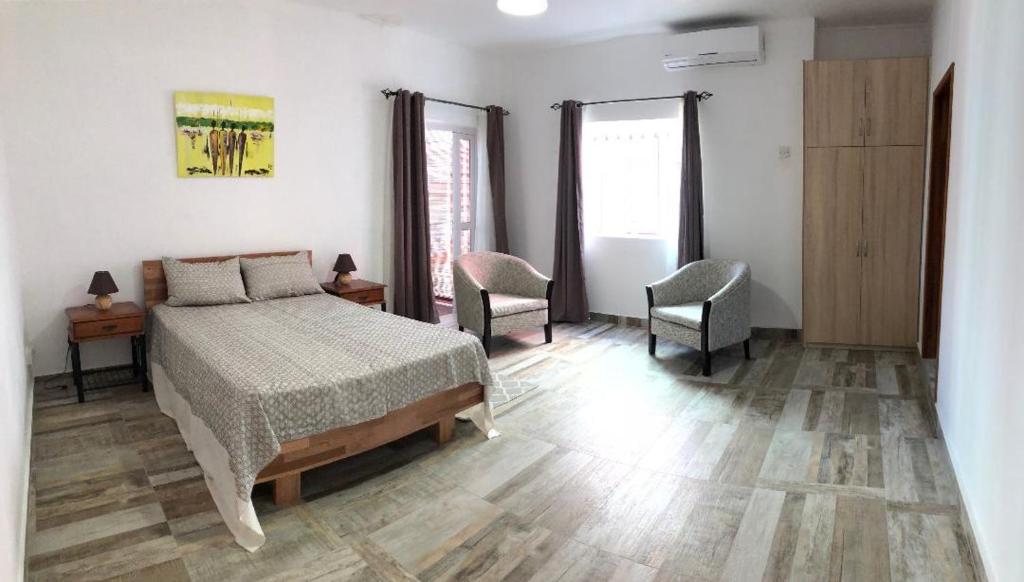 a bedroom with a bed and two chairs at Kays Residence in Pereybere