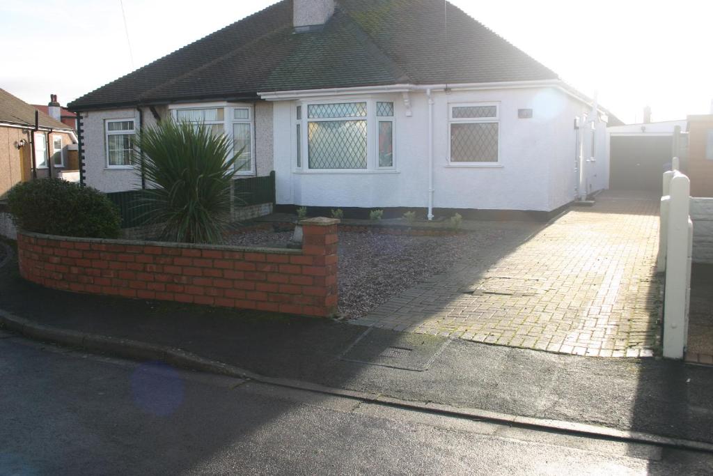 a white house with a brick fence in front of it at Beach Links in Prestatyn