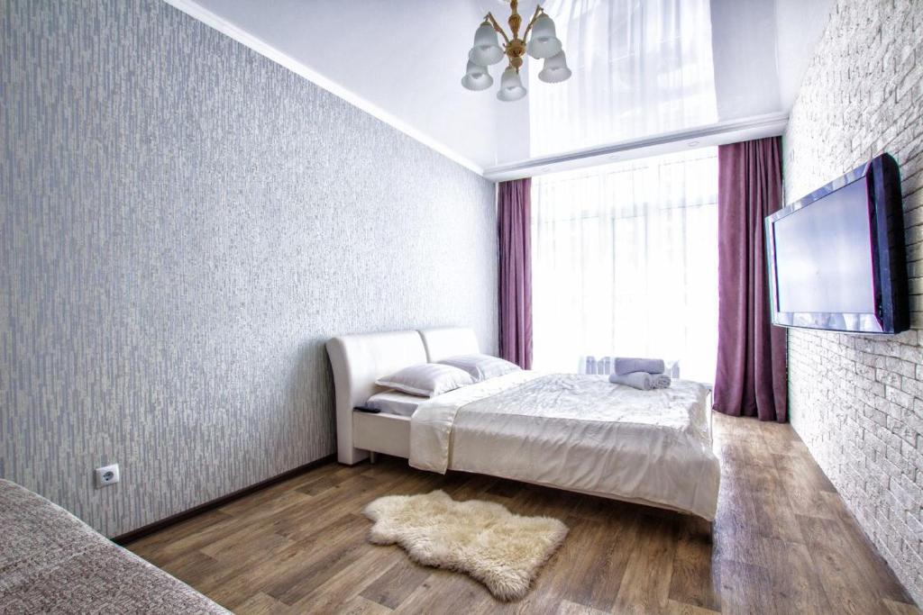 a bedroom with a bed and a flat screen tv at Однокомнатная элитная квартира в районе Экспо in Astana