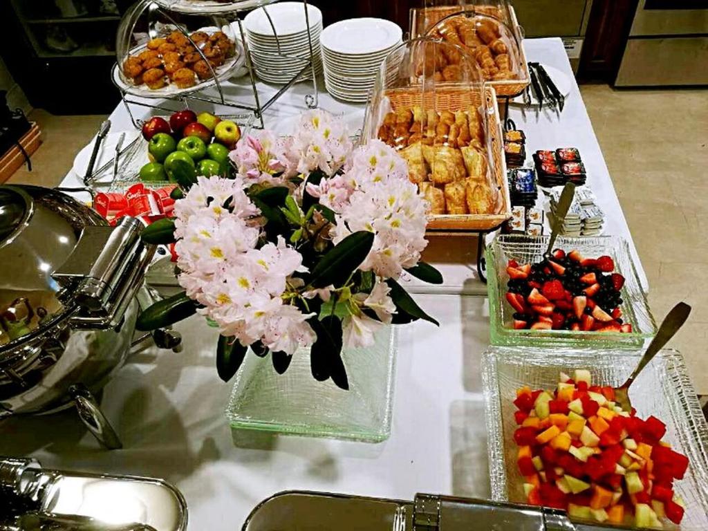 a table topped with vases filled with flowers and fruit at Sydney Boutique Inn & Suites in Charlottetown
