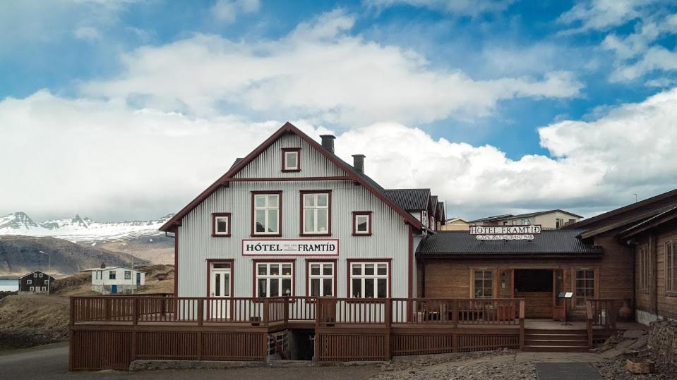 un grand bâtiment blanc avec une clôture devant lui dans l'établissement Hotel Framtid, à Djúpivogur