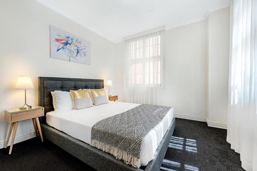 a white bedroom with a bed and a window at ULTIQA Rothbury Hotel in Brisbane