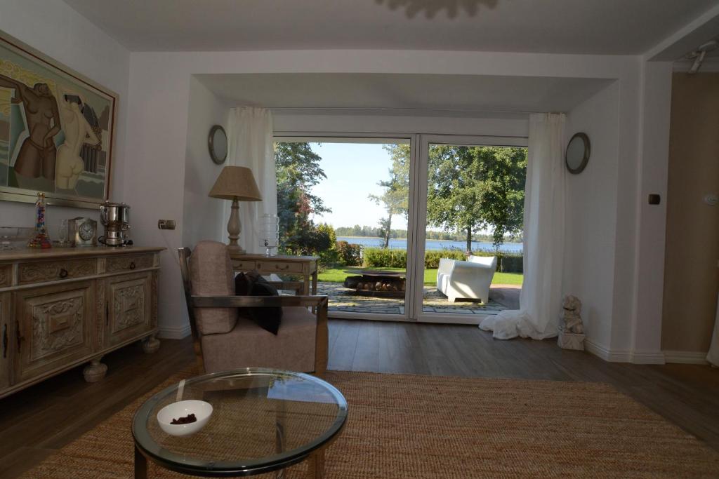 uma sala de estar com uma mesa de vidro e uma grande janela em Mazurska Villa Deluxe w Pasymiu z prywatnym pomostem na jezioro Kalwa i łodzią na wyłączność Najwyższe Premium w Osada Zamkowa em Pasym
