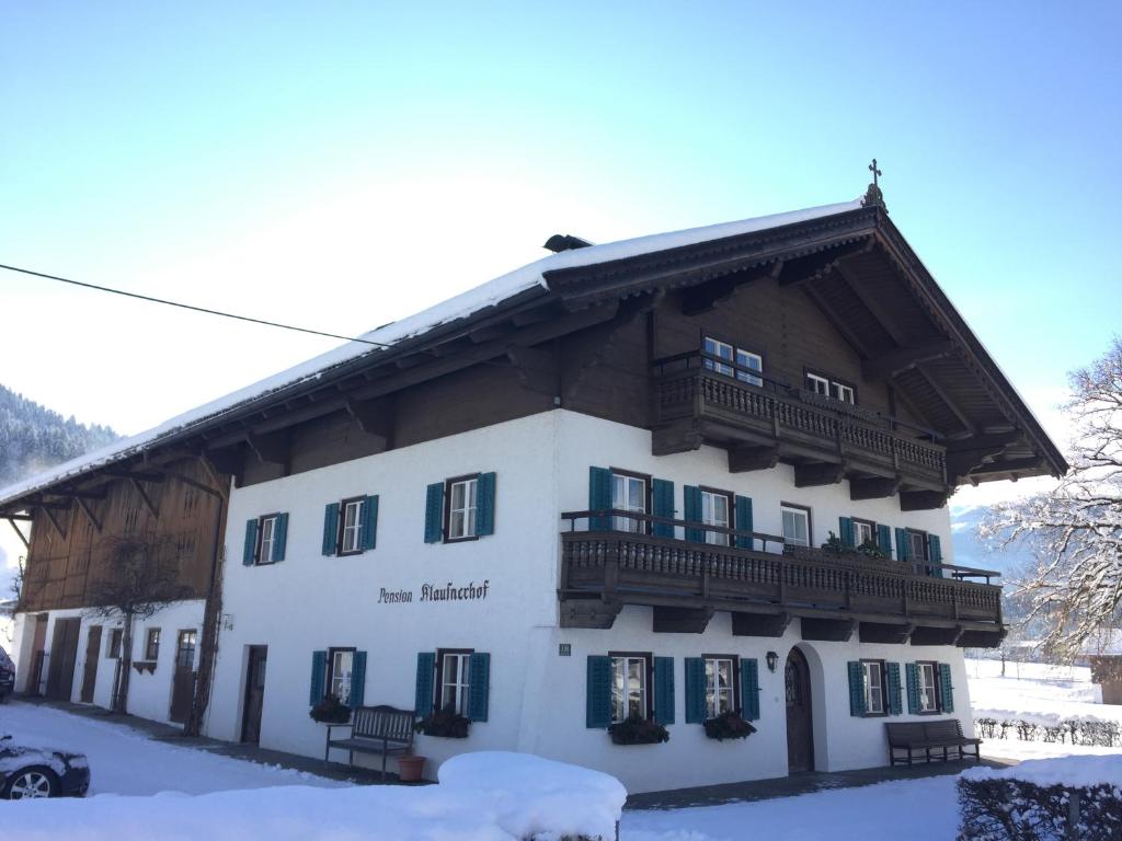 ein großes weißes Gebäude mit einem Holzdach in der Unterkunft Pension Klausnerhof in Westendorf