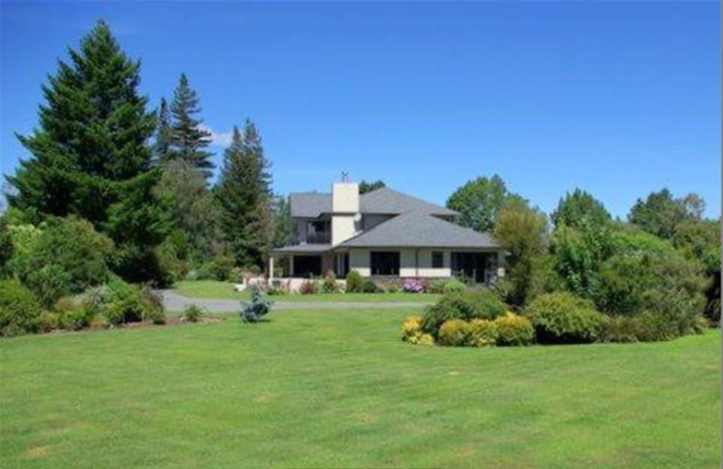 ein Haus mit einem großen Garten mit grünem Rasen in der Unterkunft Tui Lodge in Turangi