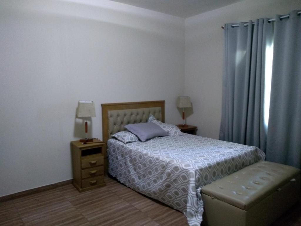 a bedroom with a bed and a window with blue curtains at Frente a Praia. Ótima casa barra de são João Rio das ostras,fino acabamento in Barra de São João