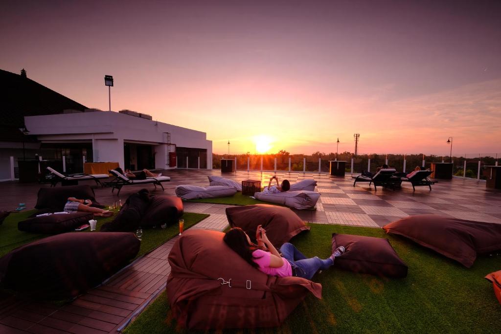 a group of people laying on pillows on a patio with the sunset at The Sintesa Jimbaran Bali in Jimbaran