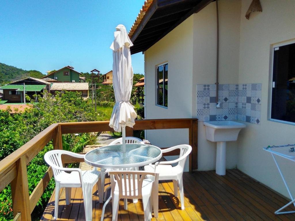 a patio with a table and chairs and an umbrella at Moradas Cantinho da Guarda in Guarda do Embaú