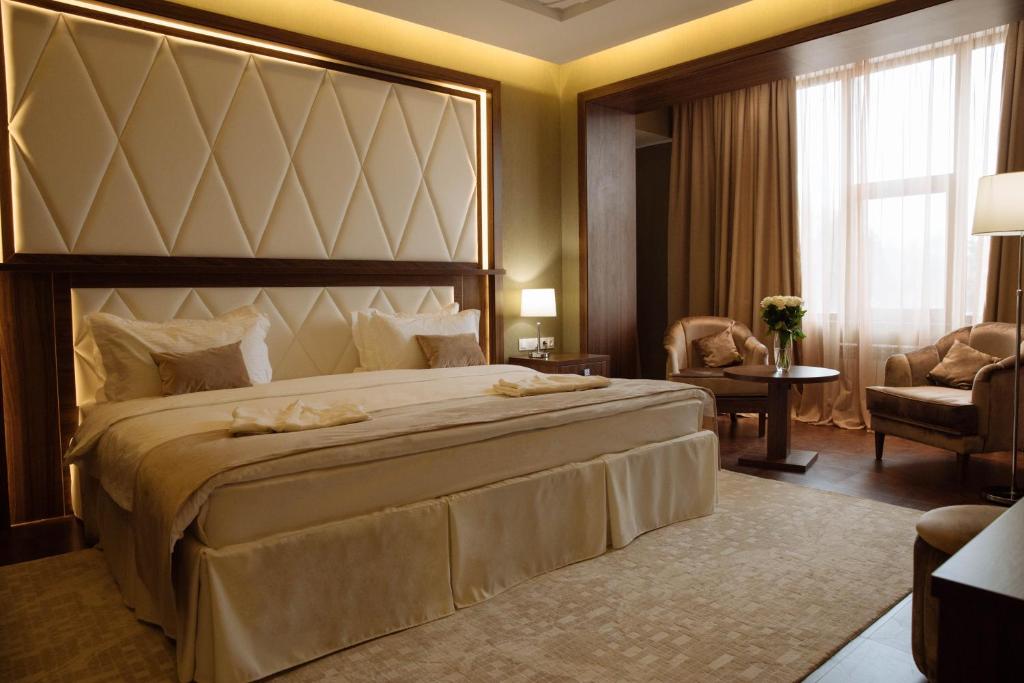 a bedroom with a large bed and a living room at Garden Park Inn in Almaty