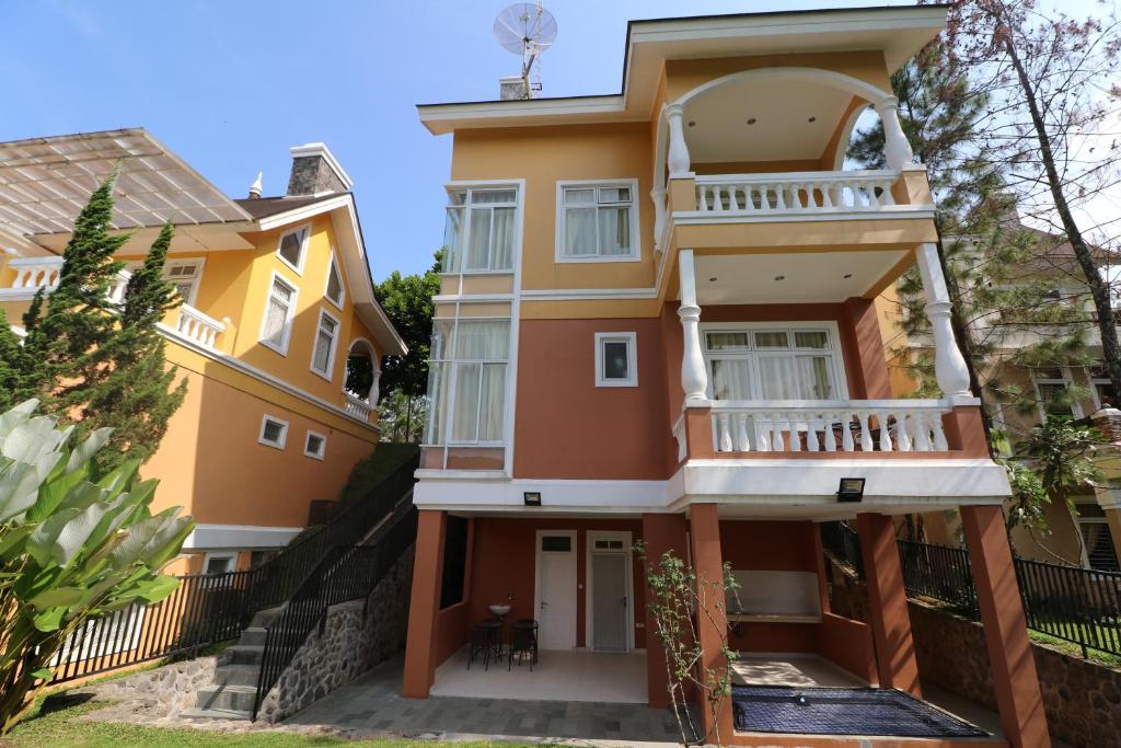 a yellow house with a balcony at Diyar Villas Puncak NB3/3 in Puncak