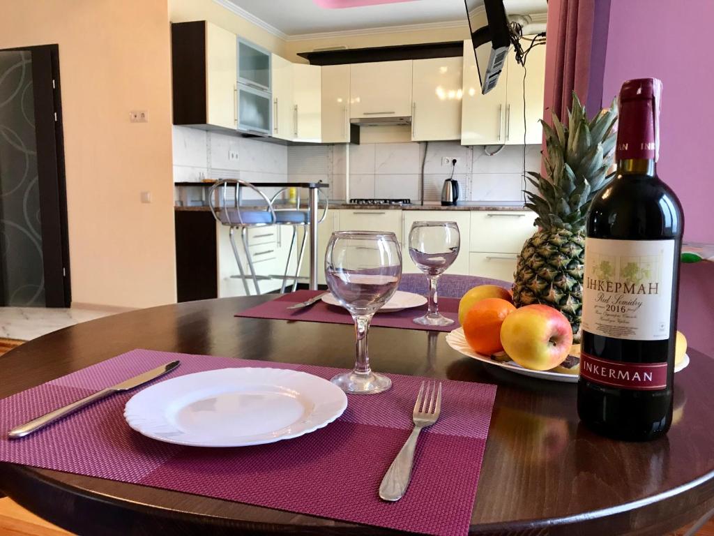 a table with a bottle of wine and a plate of fruit at Apartments in the center in Truskavets