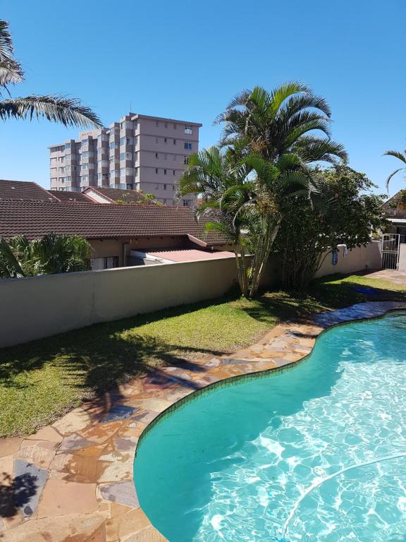 una piscina en un patio con palmeras en 11 Villa Del Sol en Amanzimtoti