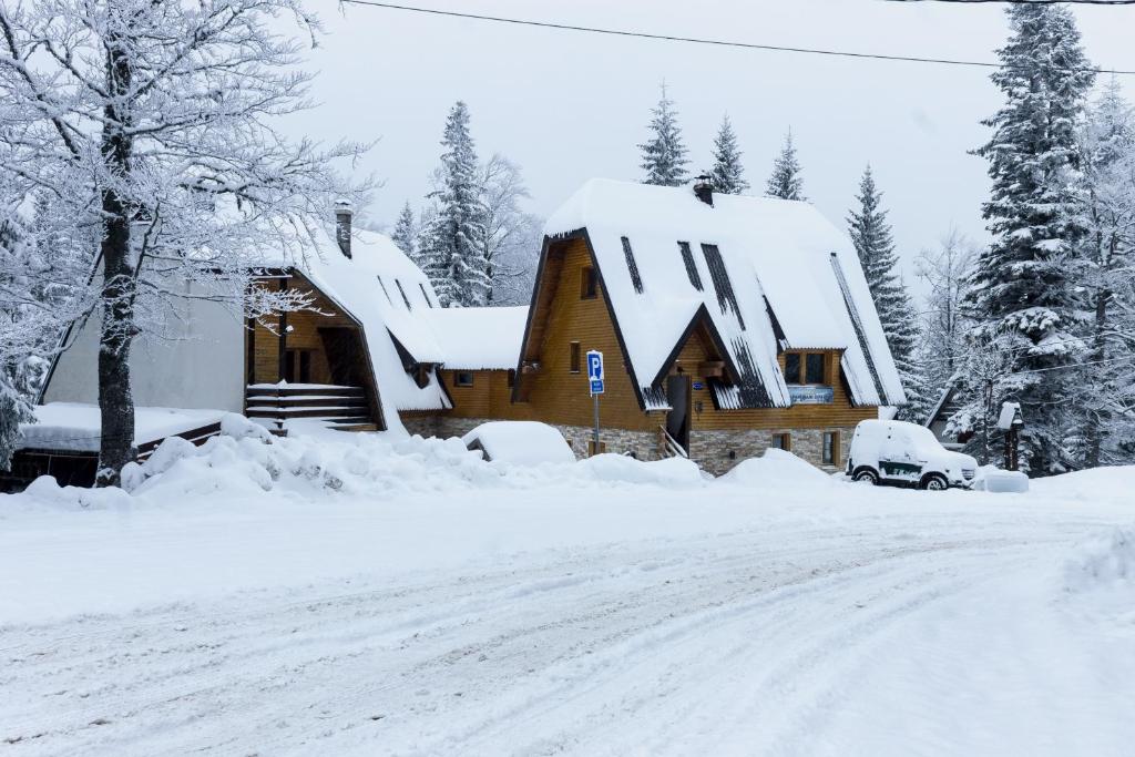 uma casa coberta de neve numa estrada coberta de neve em Apartments Dobro em Jahorina