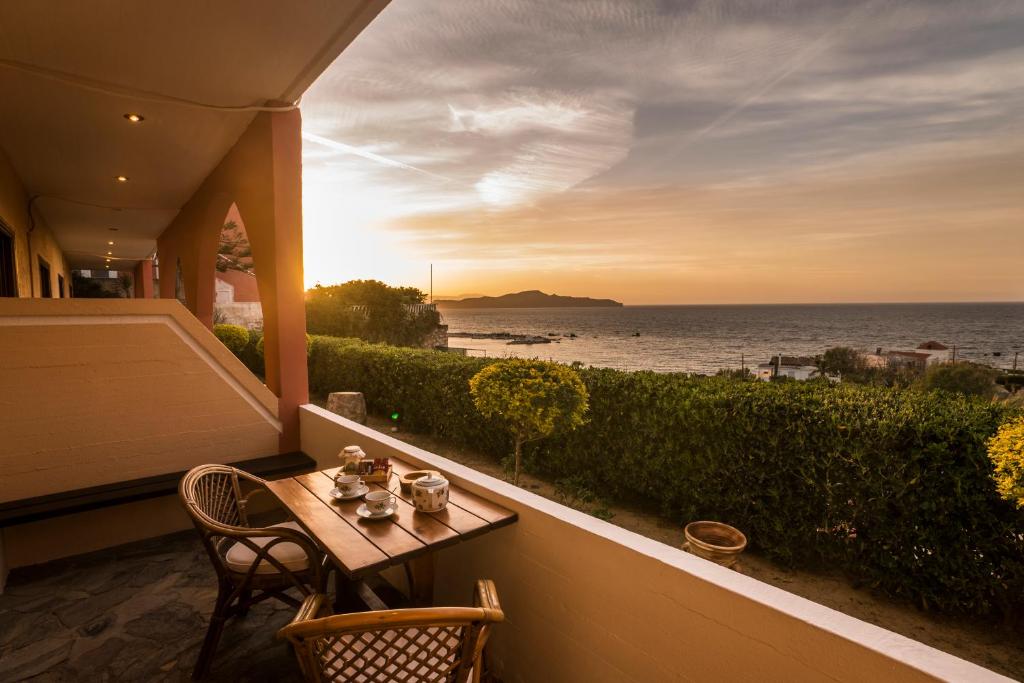 een tafel en stoelen op een balkon met uitzicht op de oceaan bij Villa Georgia Apartments & Suites in Kalamaki